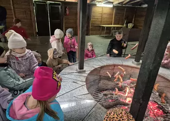 Przedszkolaki smażą kiełbaski nad ogniskiem