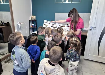 Fryzjerka pokazuje dzieciom paletę farb do włosów.