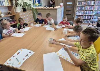 Dzieci wypełniają wakacyjne karty pracy.