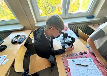 Uczeń klasy 4 obserwuje obiekty przez mikroskop