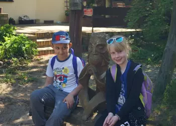 Uczeń i uczennica przy posągu małpy