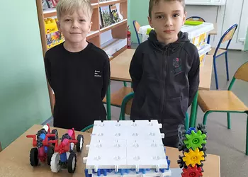 Uczniowie prezentują garaż i samochody zbudowane z klocków Korbo