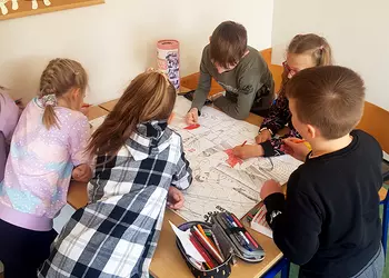 Dzieci na świetlicy wspólnie wykonują sportową kolorowankę