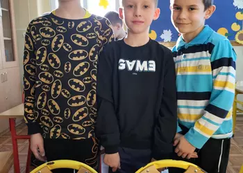 Trzech uczniów prezentuje budowlę z klocków LEGO