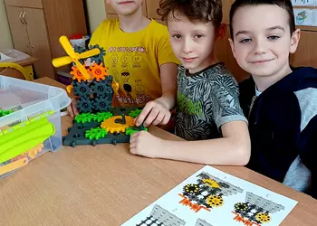 Trójka chłopców układa konstrukcję z klocków