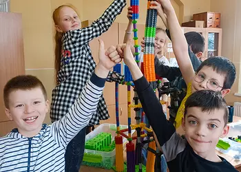 Uczniowie podtrzymują wieżę z klocków