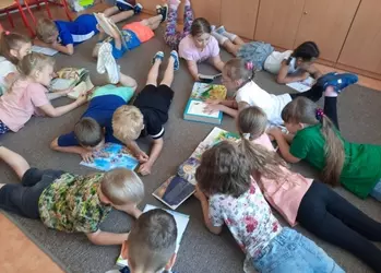 Uczniowie klasy pierwszej kontynuujący czytanie w swojej klasie na dywanie