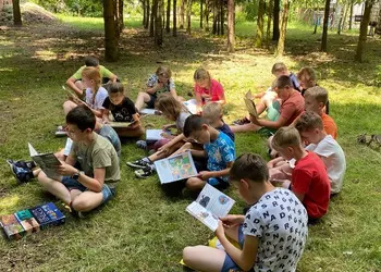 Uczniowie z filii w Wonieściu czytający książki w szkolnym ogrodzie