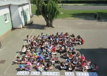 Uczniowie ze Starej Przysieki Drugiej czytający książki na dziedzińcu szkolnym