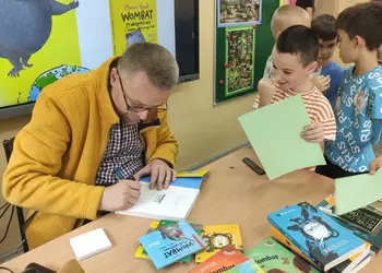 Marcin Kozioł podpisujący książkę uczniowi