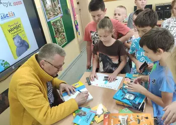 Pisarz Marcin Kozioł podpisujący książkę uczennicy