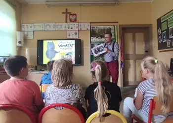 Pisarz Marcin Kozioł prezentujący swoją książkę uczniom klasy trzeciej